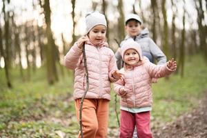 três crianças caminhada e descobrindo Primavera floresta. feliz infância. foto