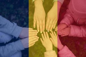 mãos do crianças em fundo do romênia bandeira. romena patriotismo e unidade conceito. foto