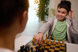 concentrado caucasiano escola Garoto em desenvolvimento xadrez estratégia, pensando em xadrez movimento enquanto jogando com dele mãe. lógica desenvolvimento, lazer borda jogos, entretenimento e Educação conceito foto