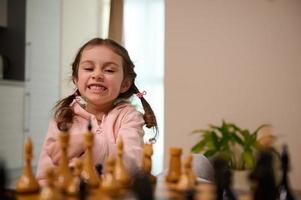 adorável 4 anos velho pequeno menina jogando xadrez jogos às lar. inteligente intelectual borda jogos para crianças, lógica desenvolvimento, Educação conceito foto