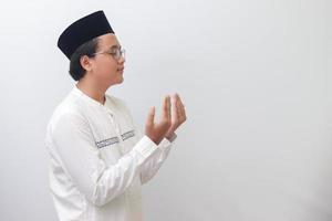 retrato do jovem milenar ásia muçulmano homem Rezar sinceramente com dele mãos criado. isolado imagem em branco fundo foto
