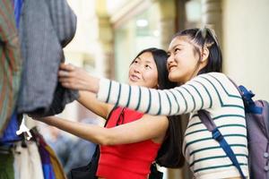 fêmea turistas olhando às roupas em rua foto