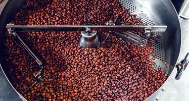 grãos de café aromáticos recém-torrados em uma moderna máquina de torrefação de café. foto