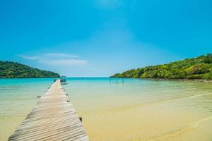 cais ou ponte de madeira com praia tropical e mar na ilha paradisíaca foto