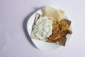 Padang cozinha, branco arroz com frango e frito Macarrão em uma branco prato em uma avião fundo foto