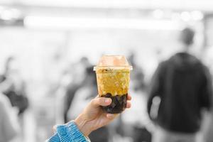 mulher mão segurando Castanho açúcar boba leite chá com tapioca pérolas às noite mercado, famoso taiwanês bolha chá do Taiwan. rua Comida e viagem dentro ximending, Taipei conceito foto