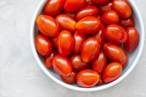 fresco vermelho cereja tomates em luz fundo foto