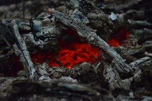 brilhando brasas dentro quente vermelho cor. a quente brasas dentro a meio do queimado madeira Histórico. lenha queimando em grade. natureza textura. foto