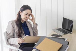 Mulher de negócios asiática com dor de cabeça no escritório foto