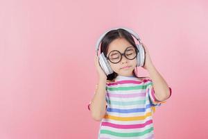 Ásia pequeno menina fofa colocar em fones de ouvido ter vídeo ligar distante classe com professor usando computador portátil, estude conectados em computador, Educação escolar em casa conceito foto