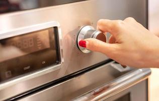 fechar-se fêmea mão abertura ou fechamento moderno elétrico forno preparar para cozinhar dentro a moderno cozinha. foto
