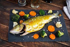 cozido mar graves peixe com legumes e verduras em pedra prato foto