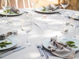 mesa às luxo Casamento recepção evento. lindo flores em mesa e servindo pratos e óculos e decoração foto