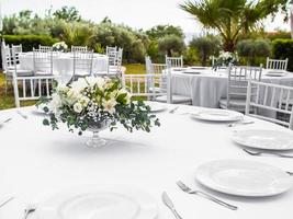 mesa às luxo Casamento recepção evento. lindo flores em mesa e servindo pratos e óculos e decoração foto