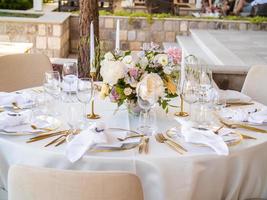 lindo ao ar livre Casamento decoração dentro cidade. velas e seco flores e acessórios com buquês e óculos em mesa com linho toalha de mesa em recém-casado mesa em verde gramado foto