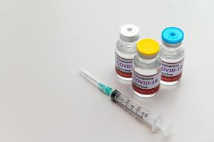 Frascos de vacina covid-19 com seringa nas mãos foto