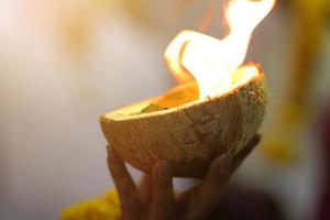 mulher mão segurando luz uma fogo dentro uma coco shel para crença e adoração a Deuses do hinduísmo dentro Tailândia foto