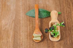 ervas remédio cápsulas a partir de erva em rústico de madeira mesa para saudável comendo e Boa vida ,macio foco. foto
