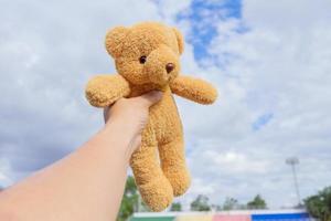 Urso brinquedo dentro mão com uma azul céu . foto