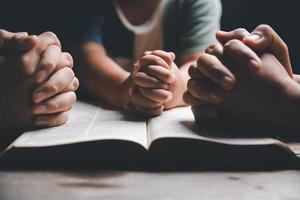 cristão família Rezar juntos conceito. criança e mãe adoração Deus dentro lar. mulher e Garoto mãos Rezar para Deus com a Bíblia implorando para perdão e acreditam dentro bondade. foto