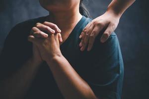 mulher deitado mãos em uma jovem fêmea cristão ombro para empoderamento e abençoar ele enquanto ele sente desanimado dentro uma casa escritório, cristão fé, e cristãos Rezar deitado em mãos conceito. foto