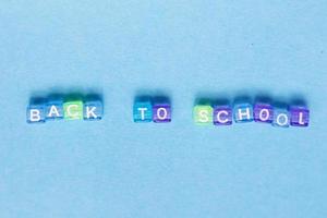 a inscrição de volta à escola feita por cubos de plástico multicoloridos sobre um fundo azul. foto