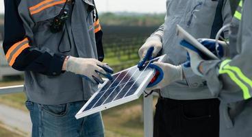 em a telhado do uma ampla solar energia armazenamento estação prédio, uma equipe do elétrico poder engenheiros teste uma pequeno solar painel este é uma protótipo instalado em centenas do acres do pastagem foto