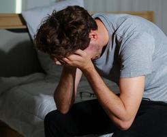 homem sentado no quarto estressado devido ao desemprego foto