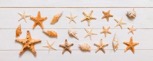 vista superior da estrela do mar e muitas conchas na vista superior do fundo de textura de madeira branca. copie o fundo do espaço, conceito de verão foto