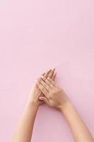mulher mostrando a manicure em fundo rosa