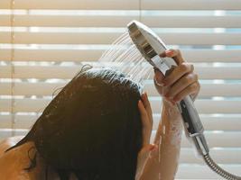 ásia mulher lavando dela cabelo relaxar a partir de trabalhos lá é luz solar foto