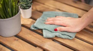 fechar acima fêmea mão limpeza de madeira mesa usando desinfetante verde toalha. evita infecção do covid-19 vírus, contaminação do germes ou bactérias, limpar ou limpeza para eliminar. foto