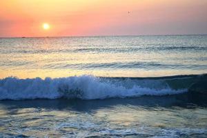 mar costa com ondas e pôr do sol foto