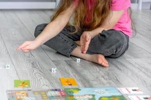 menina sentado em a chão lança dados foto