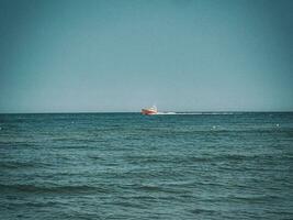 branco e vermelho mar resgate embarcação Navegando em a polonês báltico mar contra a azul céu em uma caloroso verão dia foto