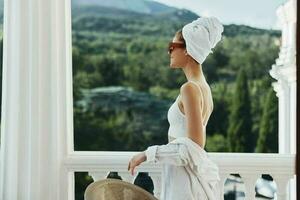 elegante mulher dentro oculos de sol em a sacada em repouso dentro a manhã foto