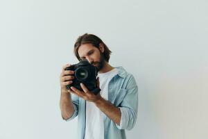 homem hipster fotógrafo dentro uma estúdio contra uma branco fundo segurando uma profissional Câmera e configuração isto acima antes tiroteio. estilo de vida trabalhos Como uma freelance fotógrafo foto