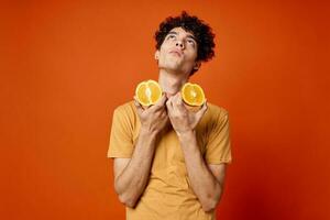 cara com encaracolado cabelo laranjas dentro mãos fruta Diversão vermelho fundo foto