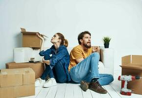 comovente renovação feliz homem e mulher em a chão dentro uma Novo apartamento com caixas foto