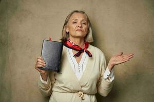 idosos mulher dentro uma vestir vestido com uma caderno dentro dela mãos estúdio trabalhos foto