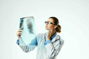 fêmea médico profissional dentro uma branco casaco olhando às a raio X para uma profissional foto