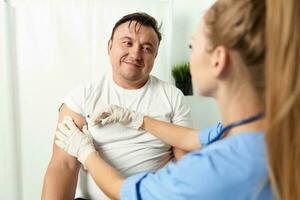 mulher médico injeções dentro a ombro do uma homem paciente saúde Cuidado cobiçado vacinação foto