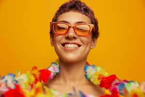 retrato do uma mulher com uma floral havaiano guirlanda por aí dela pescoço é tendo Diversão dançando e sorridente dentro brilhante roupas em a laranja fundo vestindo oculos de sol, estilo de vida festa havaiano estilo foto
