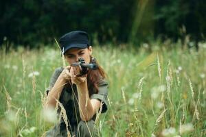 militares mulher levar cobrir com uma arma de fogo dentro mão verde macacão foto