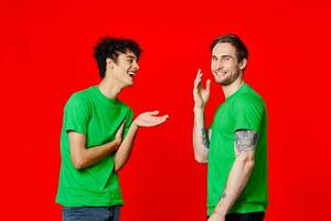 dois homens dentro verde Camisetas ficar de pé Próximo para comunicação amizade vermelho fundo foto