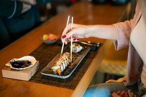 jovem mulher comendo japonês Comida com pauzinhos foto