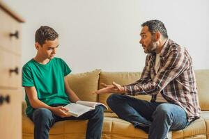 pai é ajudando dele filho com aprendizado. elas estão fazendo dever de casa junto. foto