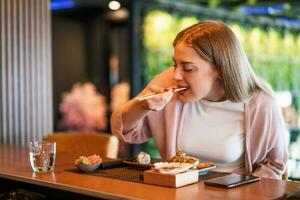 jovem mulher comendo japonês Comida com pauzinhos foto