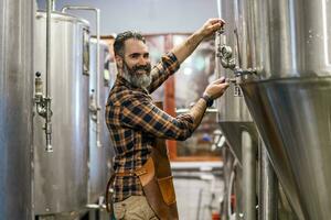 homem é trabalhando às construir Cerveja fábrica. ele é operativo maquinaria dentro cervejaria. pequeno família negócios, Produção do construir cerveja. foto