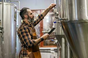 homem é trabalhando às construir Cerveja fábrica. ele é operativo maquinaria dentro cervejaria. pequeno família negócios, Produção do construir cerveja. foto